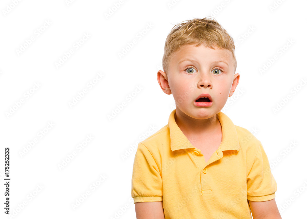 Surprised or frightened kid with a drooping jaw looks straight into the frame. Blond hair and bright eyes. Dressed in yellow polo shirt. White isolated background. Surprised or frightened kid with a drooping jaw looks straight into the frame. Blond hair and bright eyes. Dressed in yellow polo shirt. White isolated background.