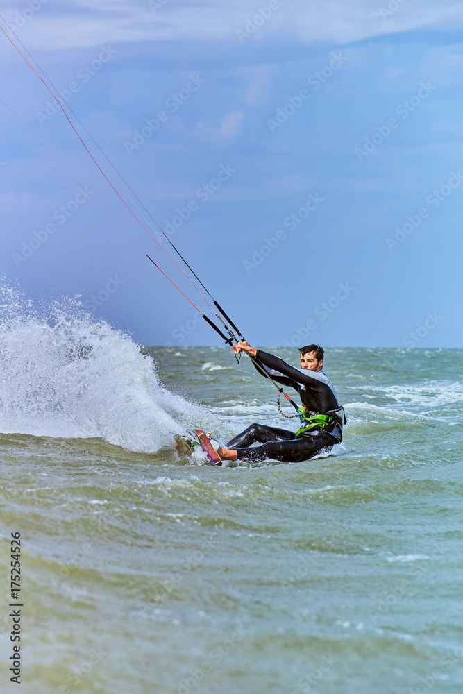 Naklejka premium Man riding a kite surfing on the waves in the summer.