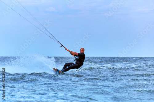 Man riding a kite surfing on the waves in the summer.