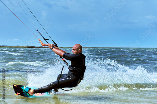Man riding a kite surfing on the waves in the summer.