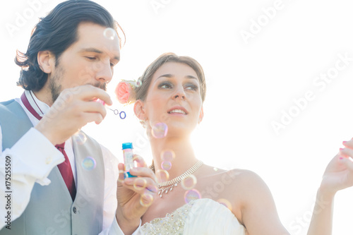 Wedding couple  bride and groom  blowing soap bubbles outside