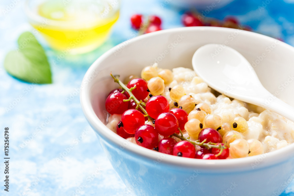 Berry oatmeal breakfast bowl on light blue background. Healthy breakfast. Selective focus, close up. Berry oatmeal breakfast bowl on light blue background. Healthy breakfast. Selective focus, close up.