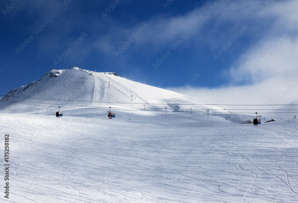 Fototapeta premium Gondola and chair lifts on ski resort at winter evening with snowfall