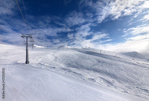 Ski slope, chair-lift on ski resort and blue sky with sunlight clouds © BSANI