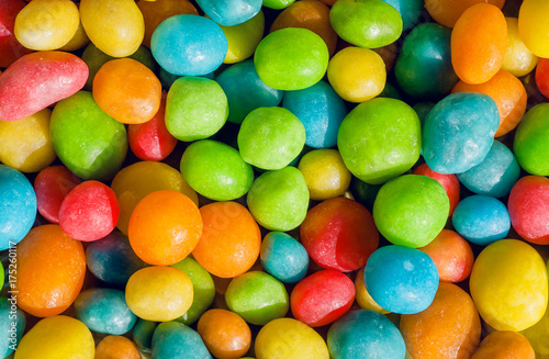 Happy colored sweets background. Many candy confection, small green, yellow, red drops. Bright texture and round forms of raisins or nuts in sugar