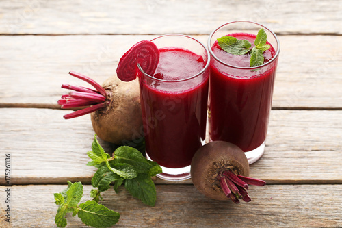 Fresh beets juice in glass on grey wooden table