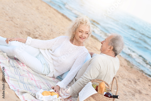 Happy senior couple having picnic on sea beach