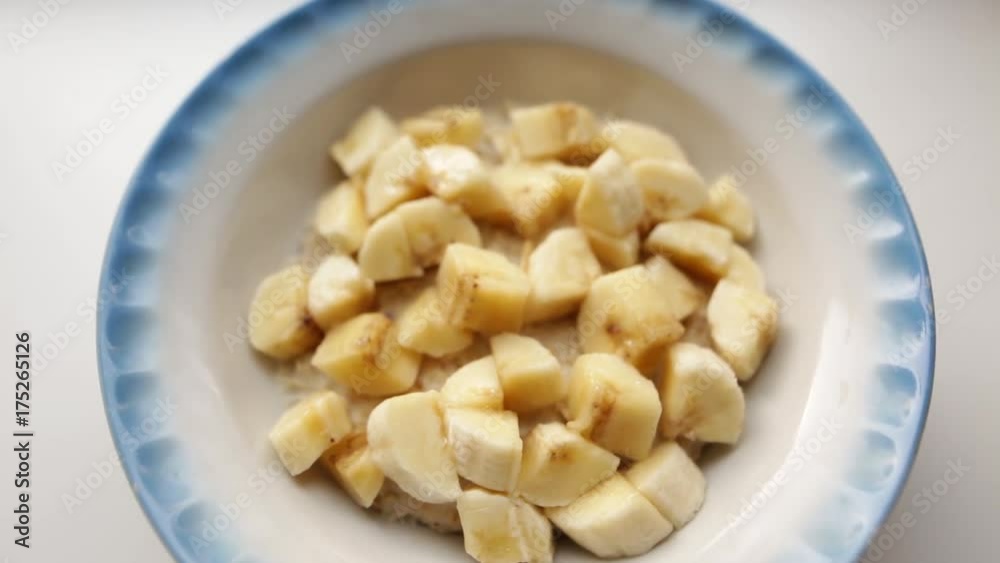 Healthy breakfast, oatmeal porridge with milk and banana. Oat flakes filled with milk in a faience dish on a white background. Organic food concept for good health. Healthy breakfast, oatmeal porridge with milk and banana. Oat flakes filled with milk in a faience dish on a white background. Organic food concept for good health.