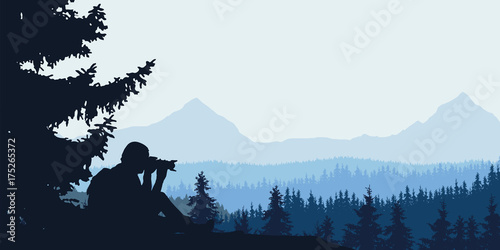 View of a man taking a forest with a mountain landscape with woods in the background under a blue-gray cloudy sky