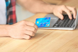Man holding credit card while using laptop indoors