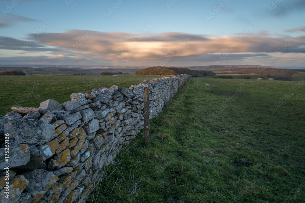 long stone wall along fields at sunset