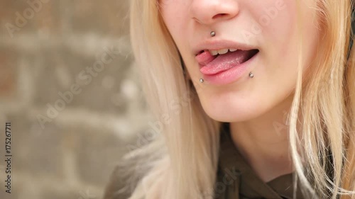 bodimodification, portrait of a girl with face piercings and tunnels in the ears. a girl with a split tongue. shows the language. 4k, slow-motion shooting, copying space photo