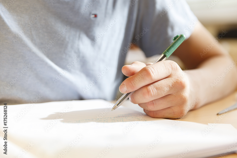 A boy holding a pen with the sun reflecting on his paper in a high school in the Netherlands in 2017. A boy holding a pen with the sun reflecting on his paper in a high school in the Netherlands in 2017.