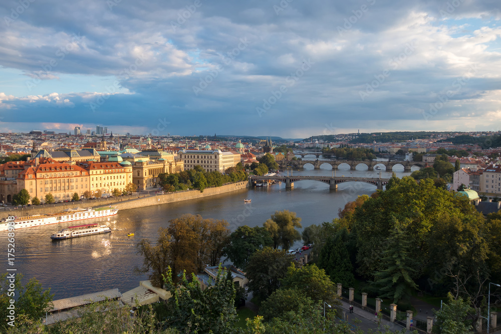 View of the city of Prague and bridges over the river Vltava in the evening.  The city is lit by the setting sun