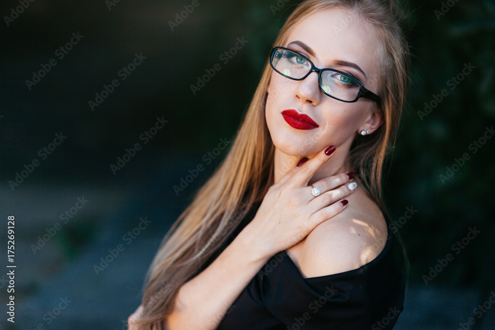 Portrait of beautiful woman in black dress, glasses and red lipstick