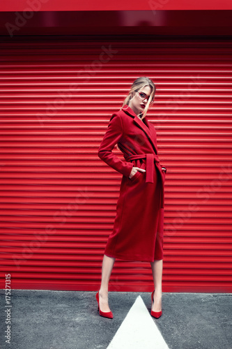 Fashion portrait stylish woman in red dress over red urban background.