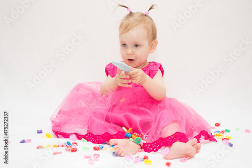 beautiful fashionable girl dressed in pink dress doing her hairstyle using comb and scrunch on white isolated background