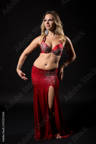 Beautiful belly dancer performing belly dance on black background.