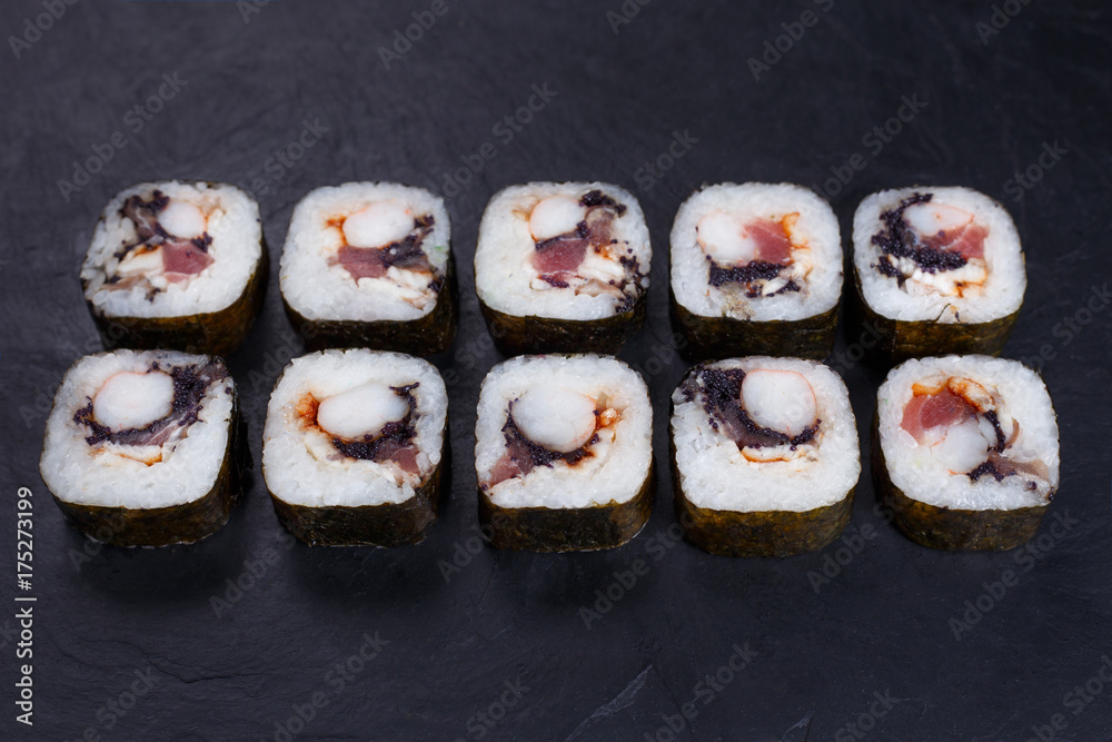 Japanese food, sushi restaurant. Delicious futomaki sushi rolls with black caviar, tuna and prawn served on black slate with free space for text design Japanese food, sushi restaurant. Delicious futomaki sushi rolls with black caviar, tuna and prawn served on black slate with free space for text design