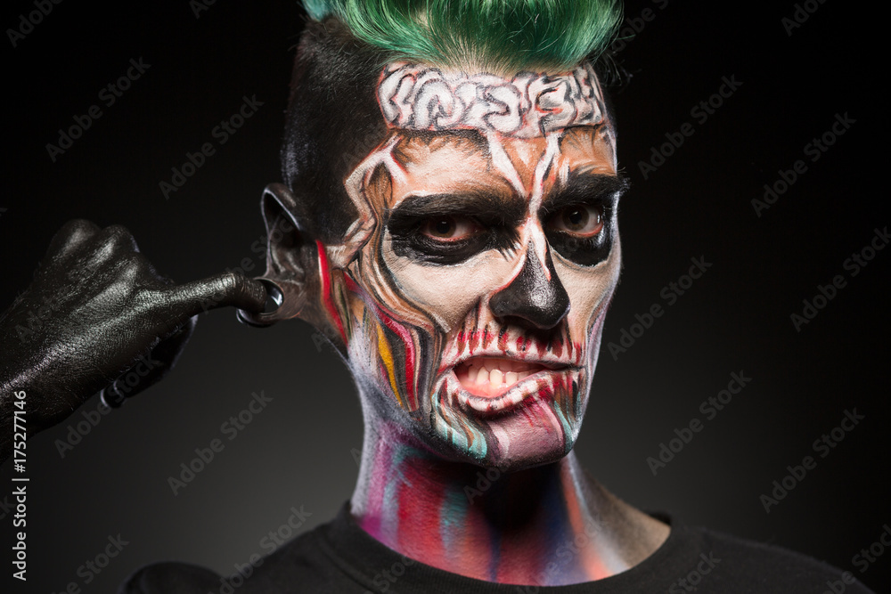 Skull face art, portrait of man with bright mystical makeup. Zombie mask on mans face isolated in black background. Skull face art, portrait of man with bright mystical makeup. Zombie mask on mans face isolated in black background.