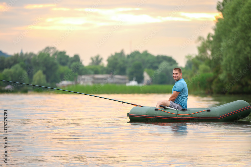 Man fishing from inflatable boat on river Man fishing from inflatable boat on river