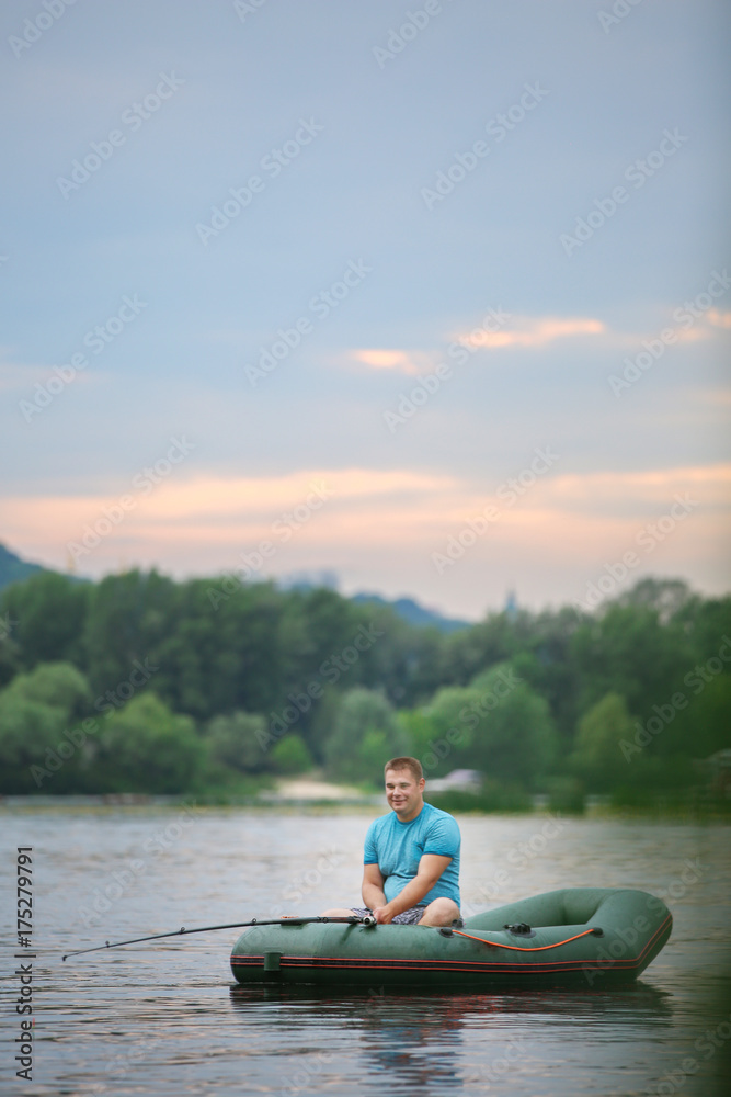 Man fishing from inflatable boat on river Man fishing from inflatable boat on river