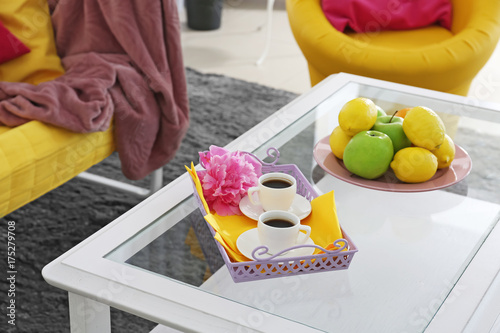 Tray with cups and fresh fruits on table in room