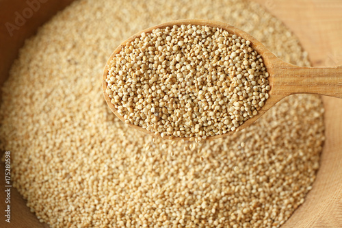 Spoon with quinoa seeds over bowl, closeup