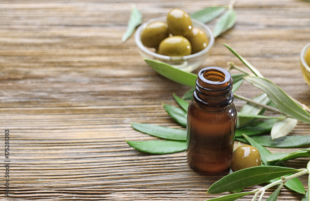 Glass bottle with olive oil on wooden table Glass bottle with olive oil on wooden table