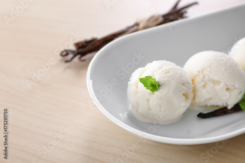 Dish with yummy vanilla ice cream balls on wooden table