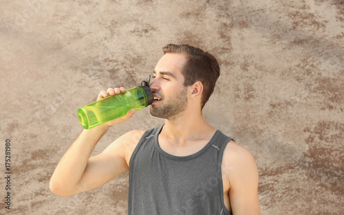 Sporty young man drinking w...
