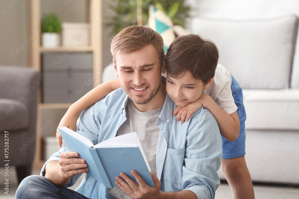 Young man and his little son reading book at home Young man and his little son reading book at home