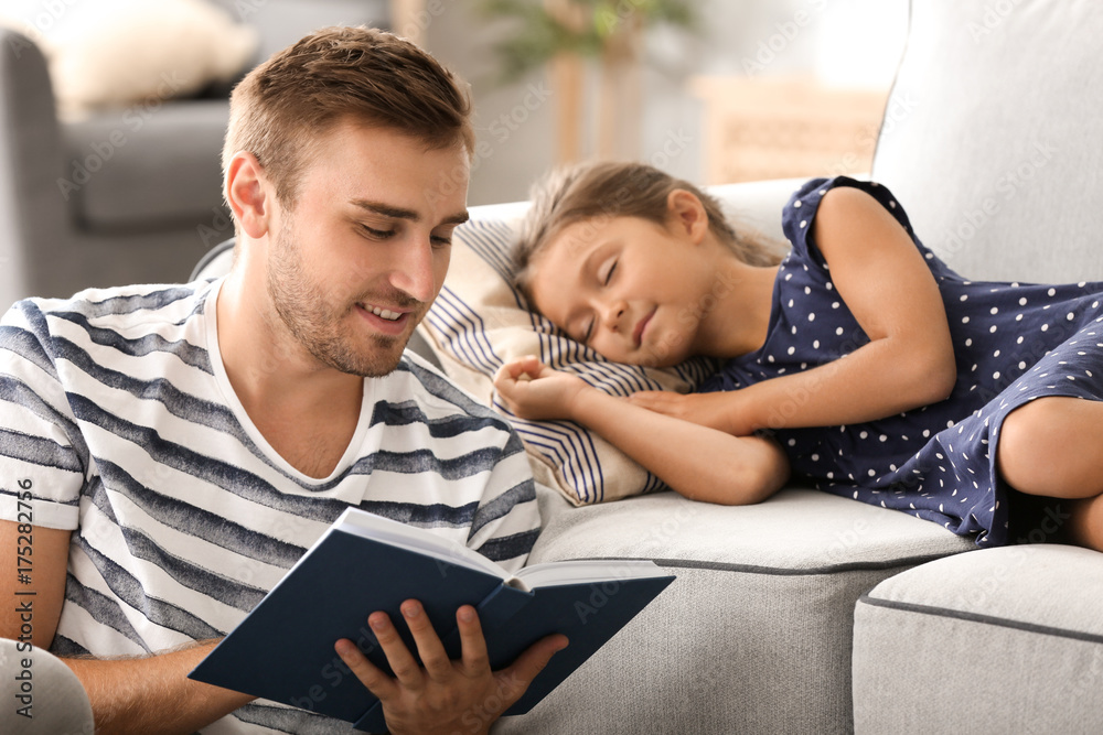 Young man reading book to his little sleeping daughter at home Young man reading book to his little sleeping daughter at home