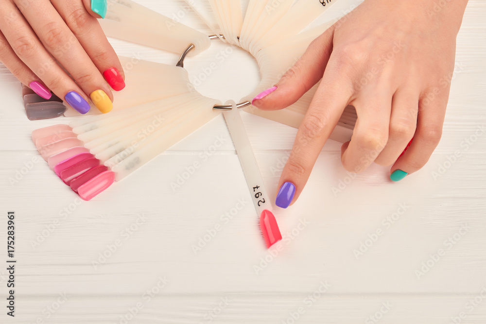 Female finger choosing nail color. Woman index finger indicating on pink color of nail color sample. Summer colors nail polish palette and female hands. Female finger choosing nail color. Woman index finger indicating on pink color of nail color sample. Summer colors nail polish palette and female hands.