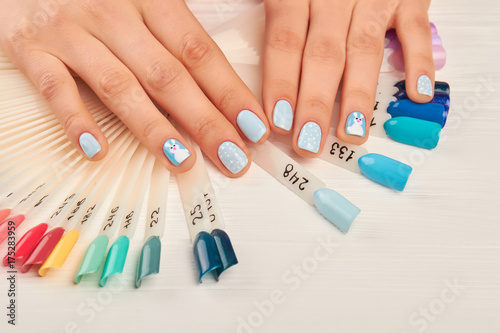 Manicured hands and nail color samples. Female hands with perfect winter manicure on nails color palette. Woman in nail salon. Variety of winter colors nail samples.