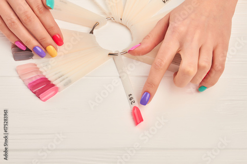 Female finger choosing nail color. Woman index finger indicating on pink color of nail color sample. Summer colors nail polish palette and female hands.