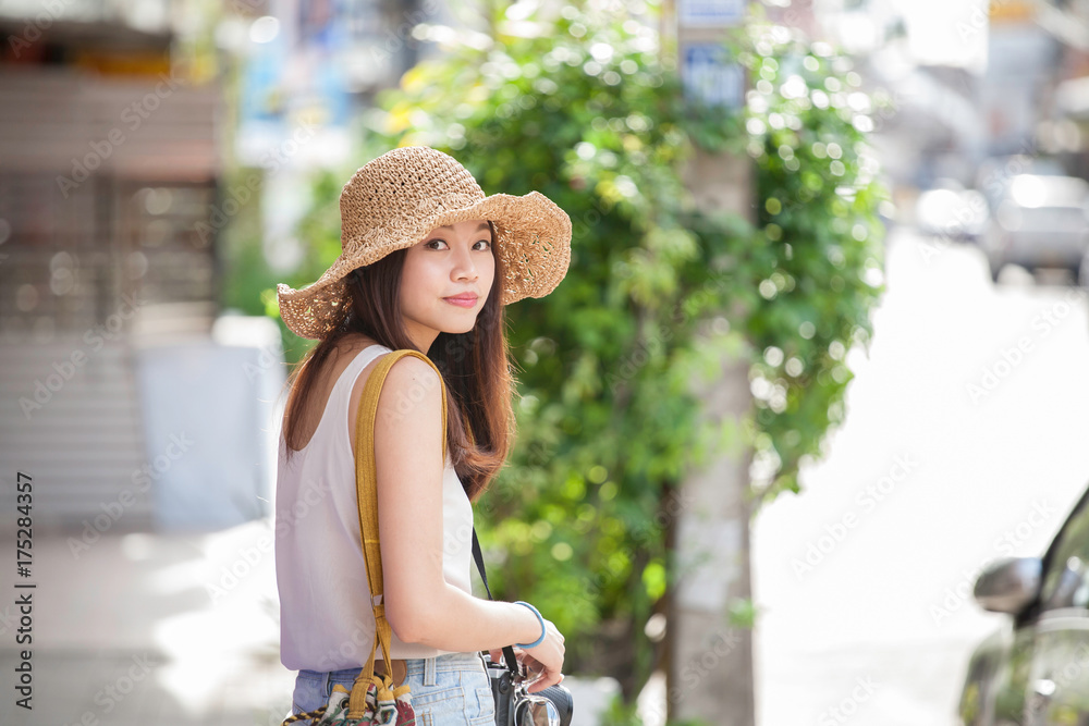 Asian woman wears hat with blurry background of city