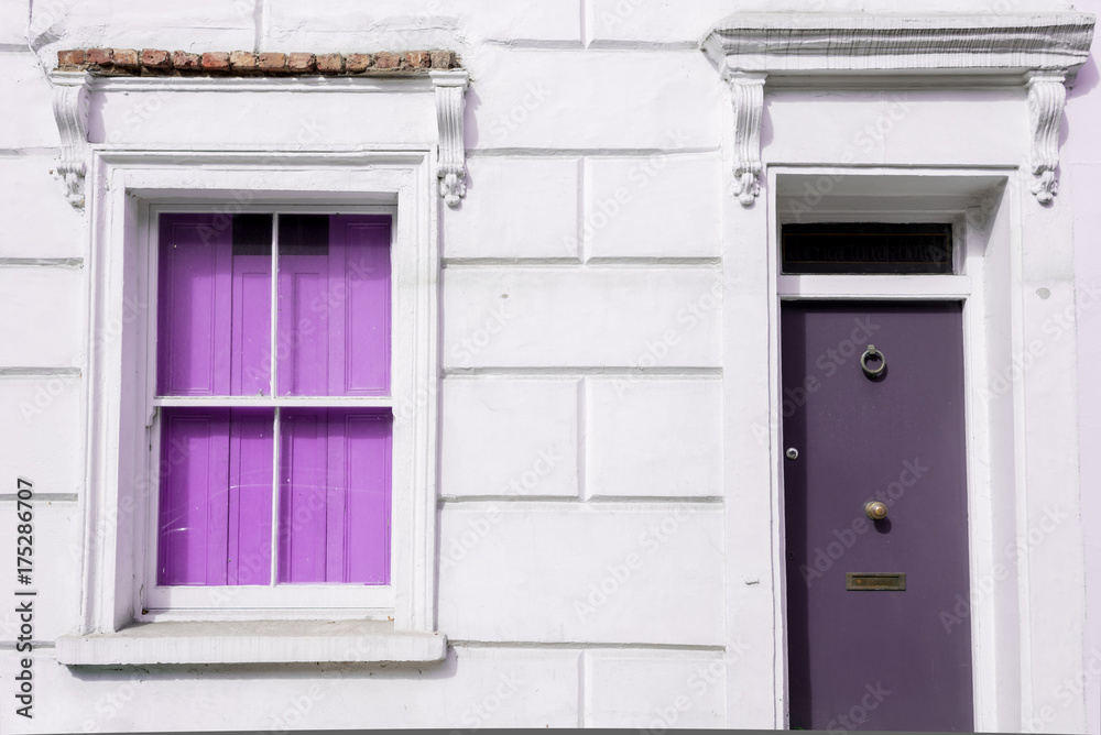 Facade of a Victorian residential building with bright violet window and door on a white wall