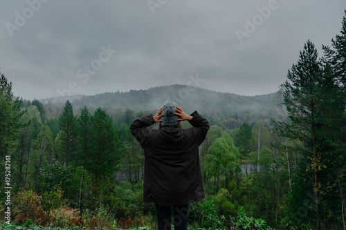 The young happy girl raised her hands up to the sun, against the mountain and sunset sky