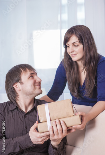 Relationships Ideas and Concepts. Portrait of Caucasian Brunette Wife Giving a Present to Her Husband.