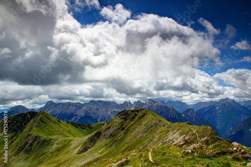 Grassy Carnic Alps main ridge with path of Karnischer Hohenweg, in background jagged Rinaldo and Terze Siera groups of Carnic Alps and Carnic Prealps, Belluno, Veneto, Northern Italy, Europe