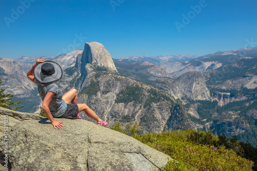 Traveler lifestyle woman looking panorama at Glacier Point in Yosemite National Park, California, USA. Wiew from Glacier Point: Half Dome, Liberty Cap, Yosemite Valley, Vernal Fall and Nevada Fall.