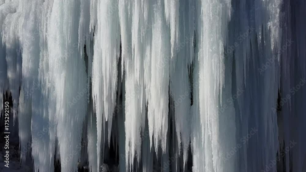 AERIAL CLOSE UP Winter cascade frozen into sparkling icicles. Stunning frozen icicles hanging from rocky mountain cliff on winter day. Early spring sun melting icy waterfall. Fantastic winter scenery AERIAL CLOSE UP Winter cascade frozen into sparkling icicles. Stunning frozen icicles hanging from rocky mountain cliff on winter day. Early spring sun melting icy waterfall. Fantastic winter scenery