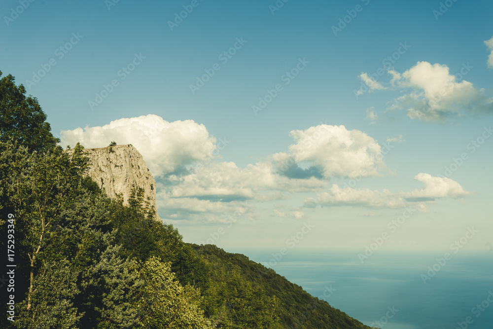 Rocky mountain amd cape of Black Sea in Ctimea, top view on blue ocean with green landscape and beautiful blue sky and white clouds. 