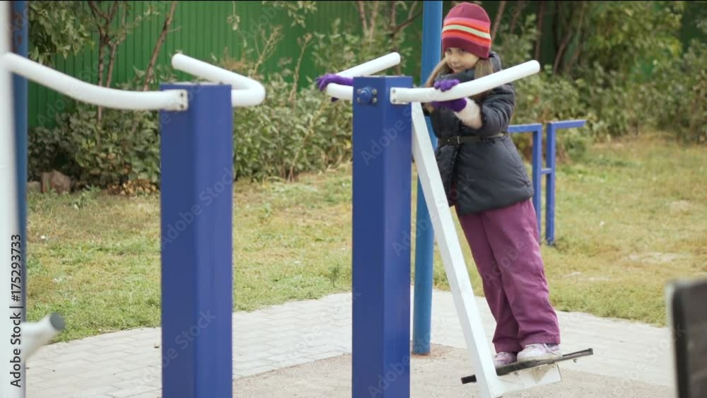 Little cute girl caucasian ethnicity is engaged on sports training apparatus on a sportsground. Slow motion. Little cute girl caucasian ethnicity is engaged on sports training apparatus on a sportsground. Slow motion.