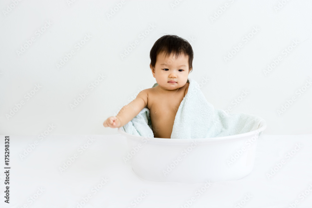 Portrait of adorable baby sitting in the basin for shower, indoors Portrait of adorable baby sitting in the basin for shower, indoors
