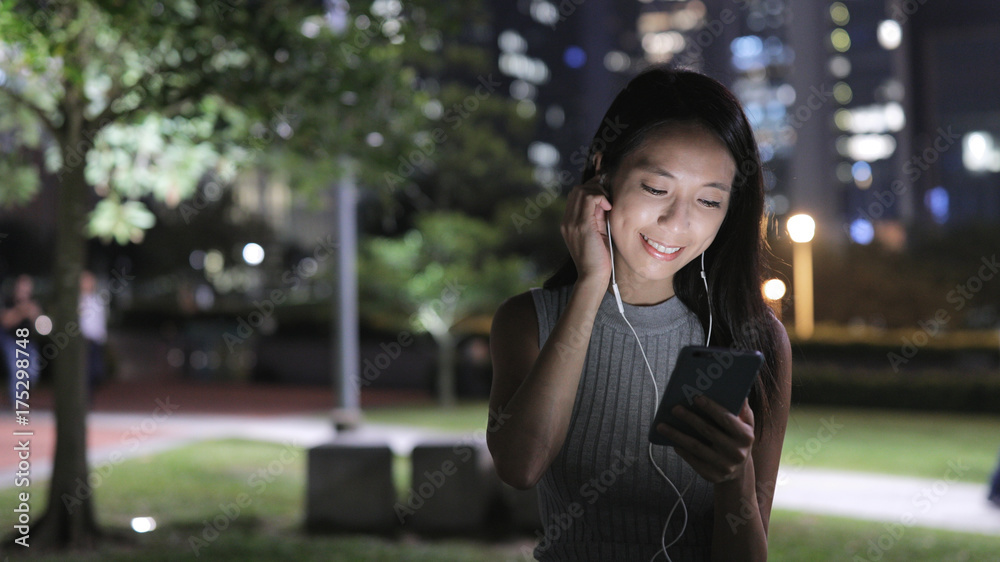 Woman listen to music on cellphone at night