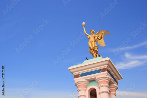 Angel statues holding lamp on blue sky