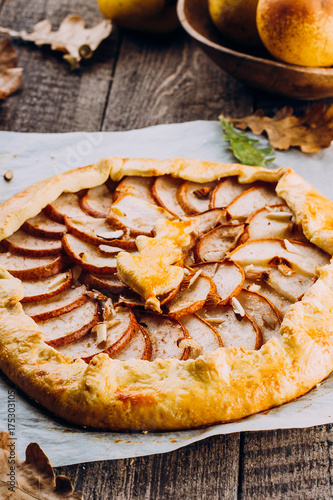 Homemade galette with pears and nuts on wooden rustic background. Sweet open fruit pie. Autumn bakery. Top view, copy space