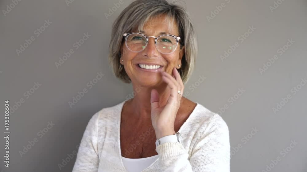 Portrait of mature woman with eyeglasses on grey background Portrait of mature woman with eyeglasses on grey background
